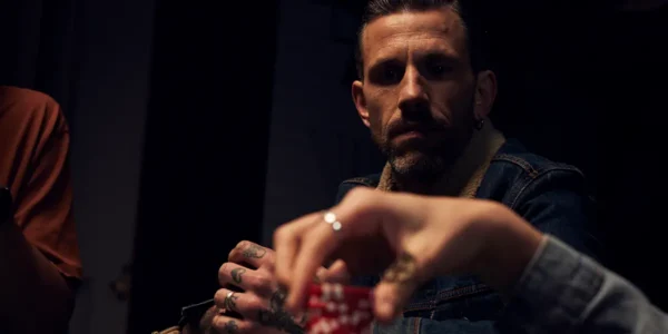 A tense live poker game at a casino table with one player closely observing their opponent's body language.